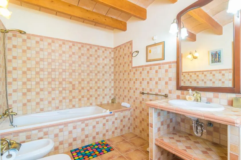 Un baño alicatado con bañera, lavabo y un espejo grande.