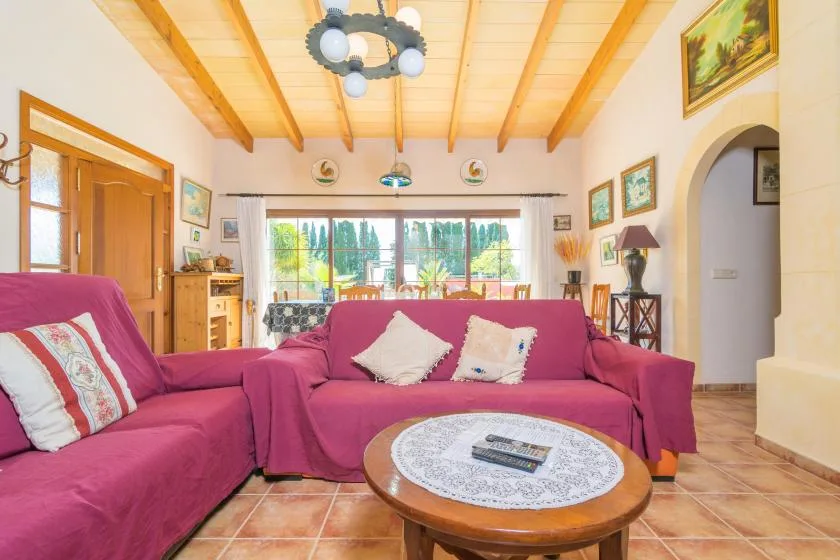 Una sala de estar con asientos magenta y una mesa de centro redonda de madera.
