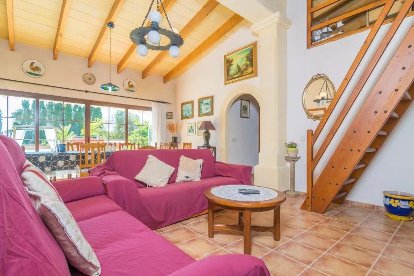 Una sala de estar con asientos rosas, una mesa de centro redonda y una escalera.