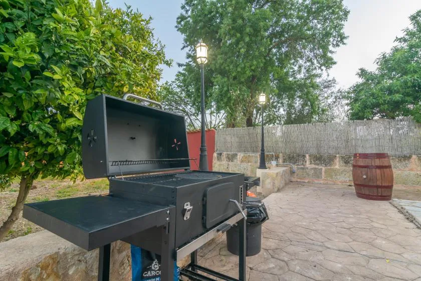 Un patio al aire libre con una parrilla y un barril de madera.