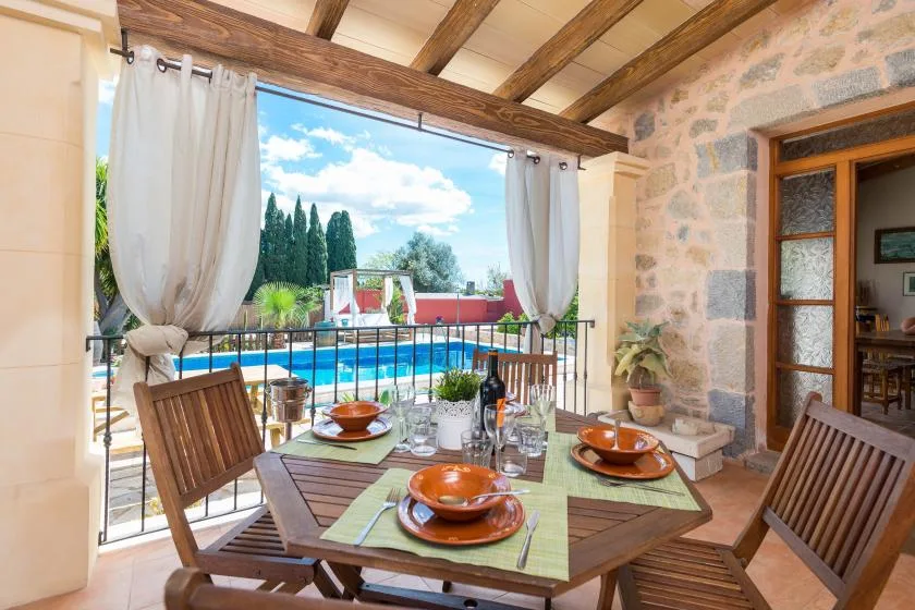 Una mesa de comedor en una terraza cubierta da a una piscina.