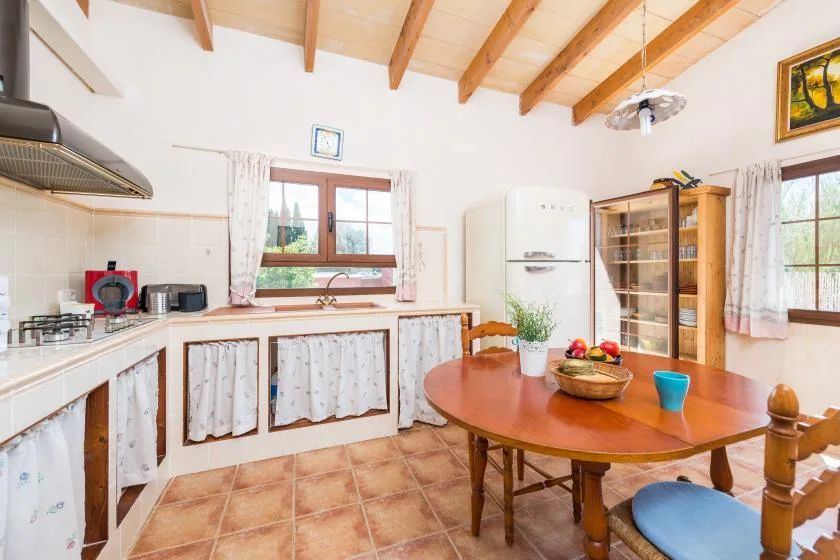 Una cocina y comedor luminosos con una mesa de madera bajo vigas expuestas.
