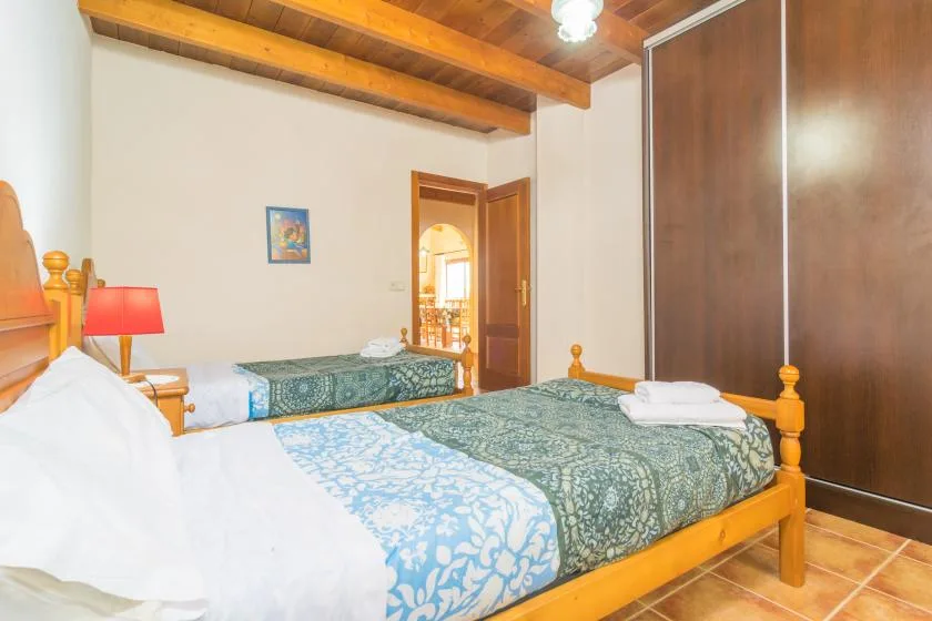 Un dormitorio con dos camas, toallas dobladas y vigas de madera en el techo.