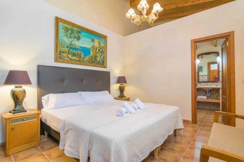 Un dormitorio con una cama bien tendida y una puerta que da a otra habitación.