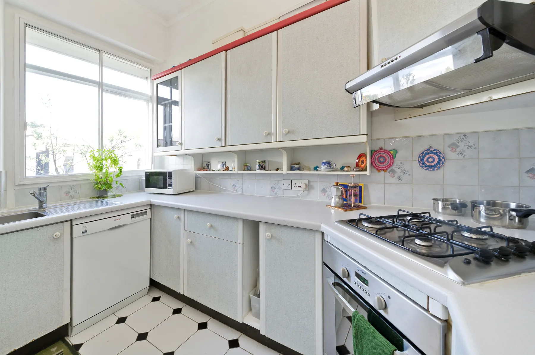 Una cocina luminosa con gabinetes blancos, una encimera y una estufa de gas.