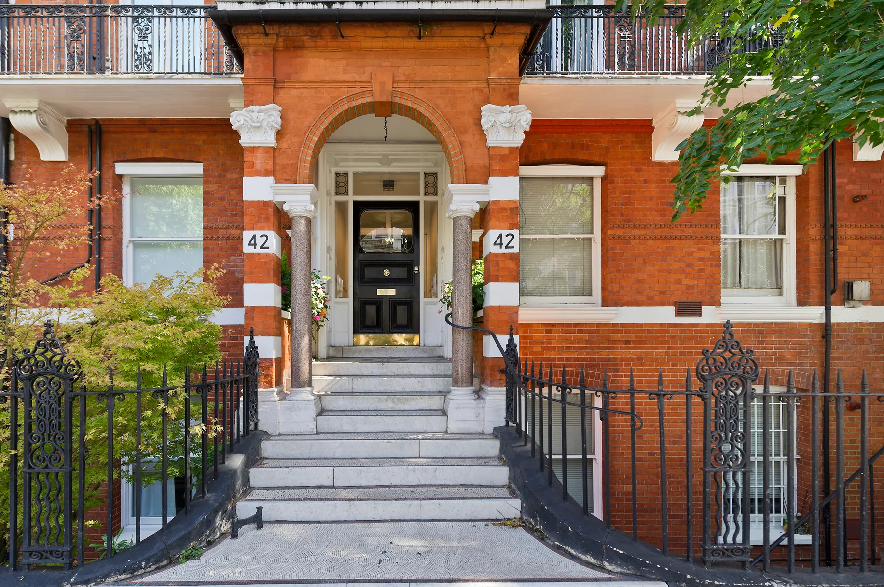 Entrada de un edificio de ladrillo rojo con puerta arqueada y escalones.
