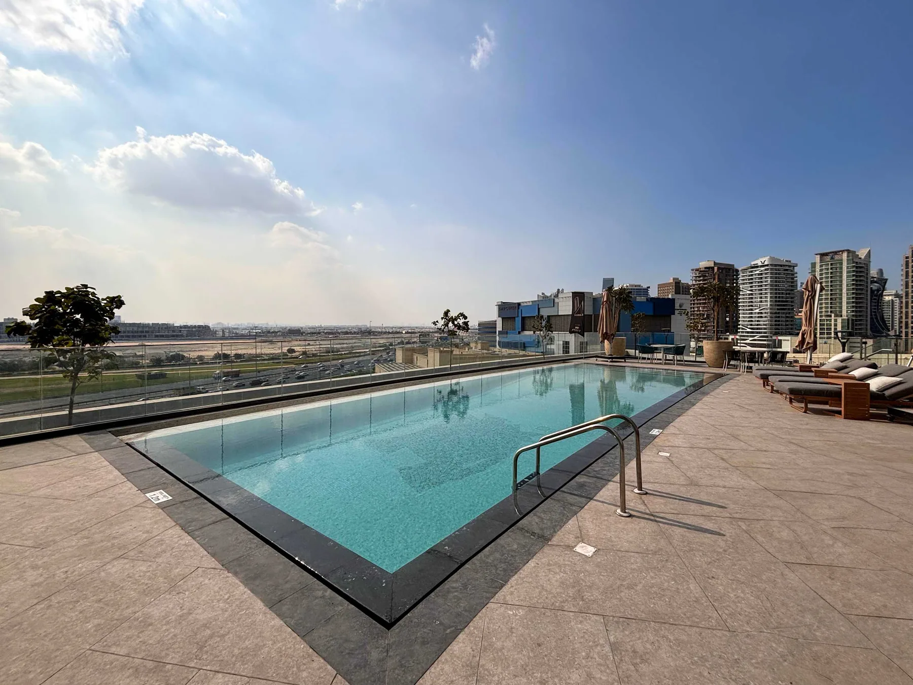 Una piscina en la azotea con asientos y el perfil urbano al fondo.