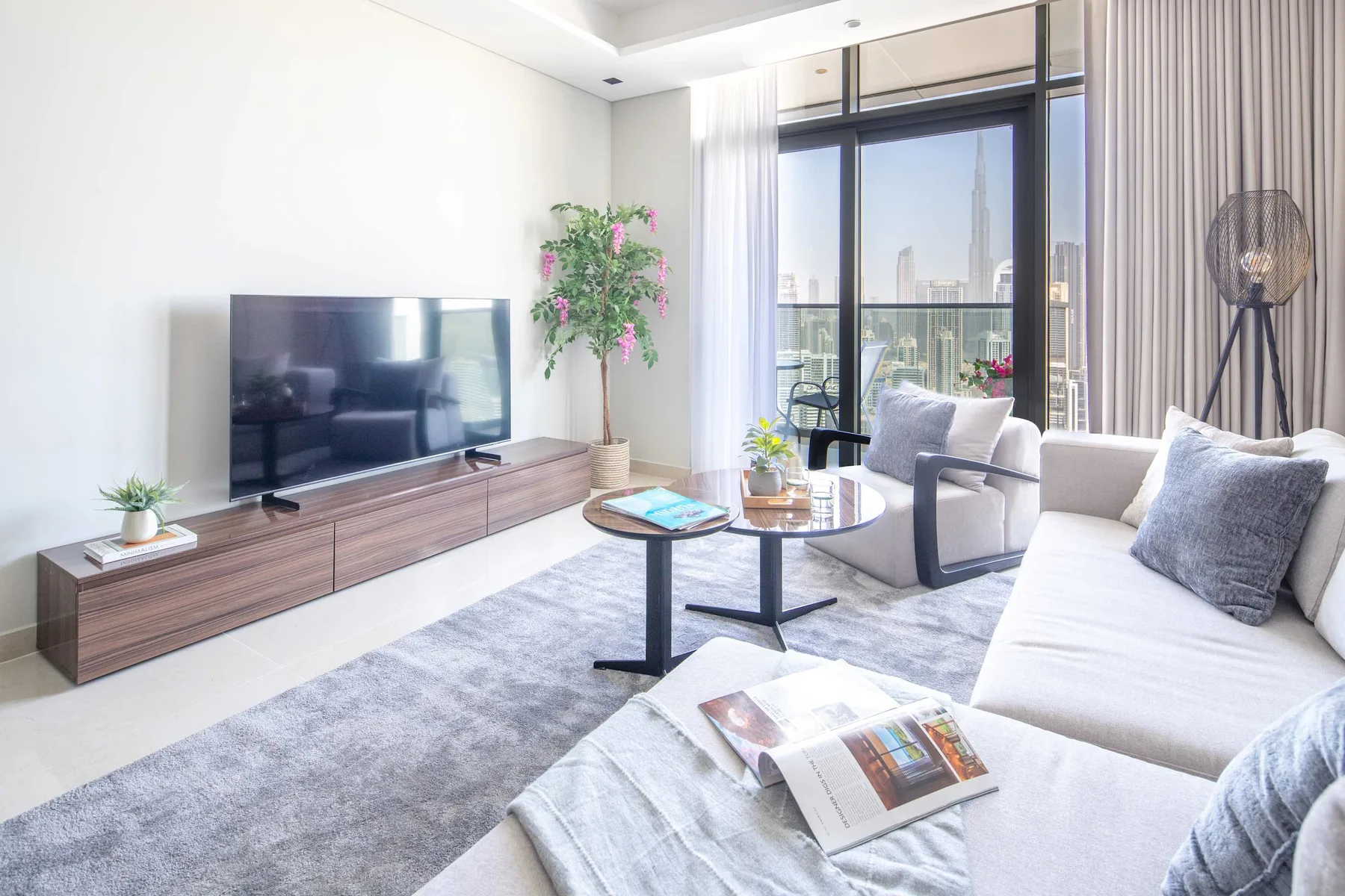 Una sala luminosa con televisor, asientos y ventanales.