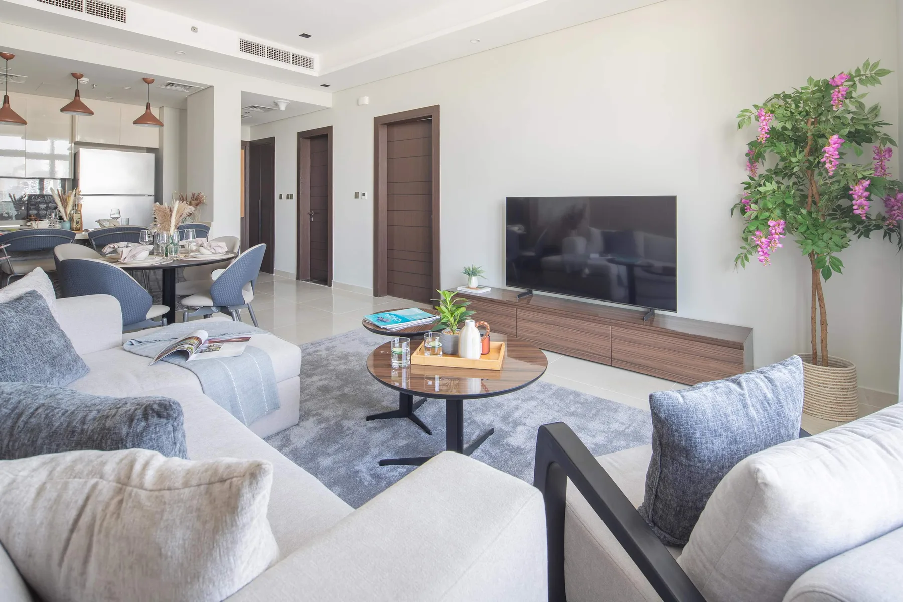Una sala de estar luminosa con asientos alrededor de una mesa de centro y un televisor.