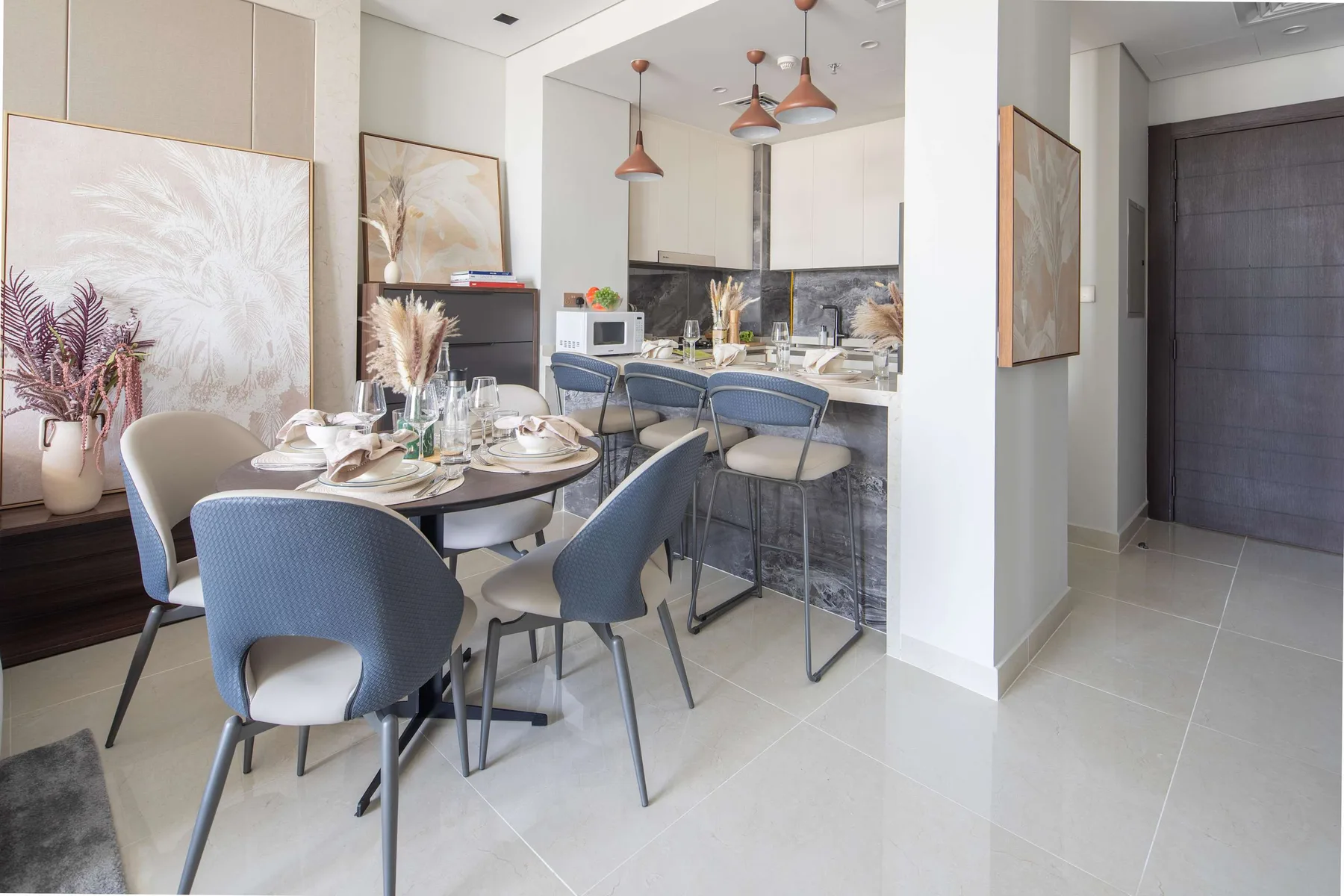 Un comedor con la mesa puesta y asientos azules junto a una barra de cocina.