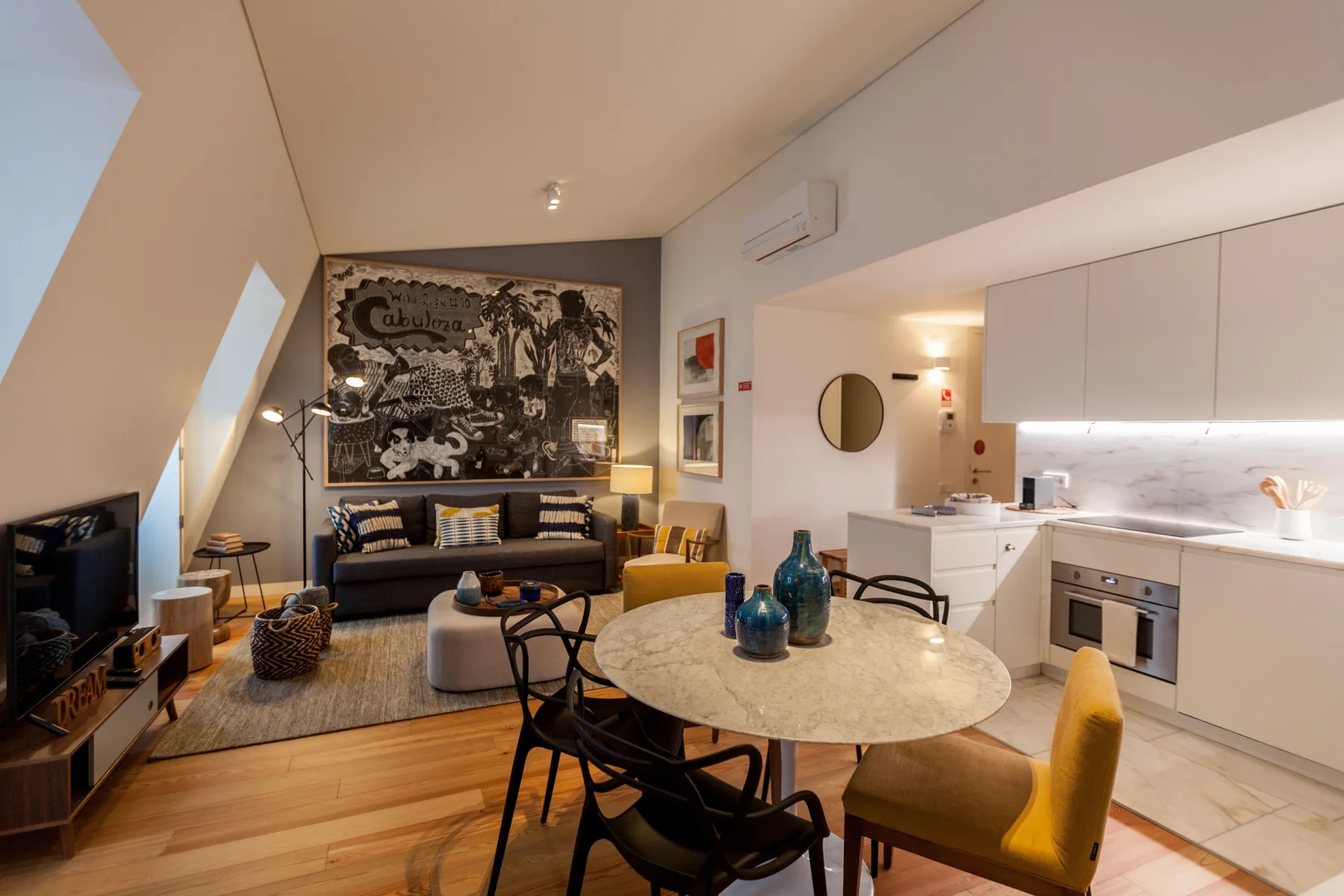 Sala de estar y comedor de planta abierta con una gran obra de arte en la pared.