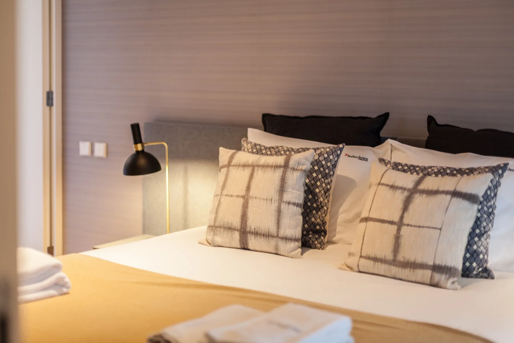 Un dormitorio con una cama bien hecha y una lámpara de noche.
