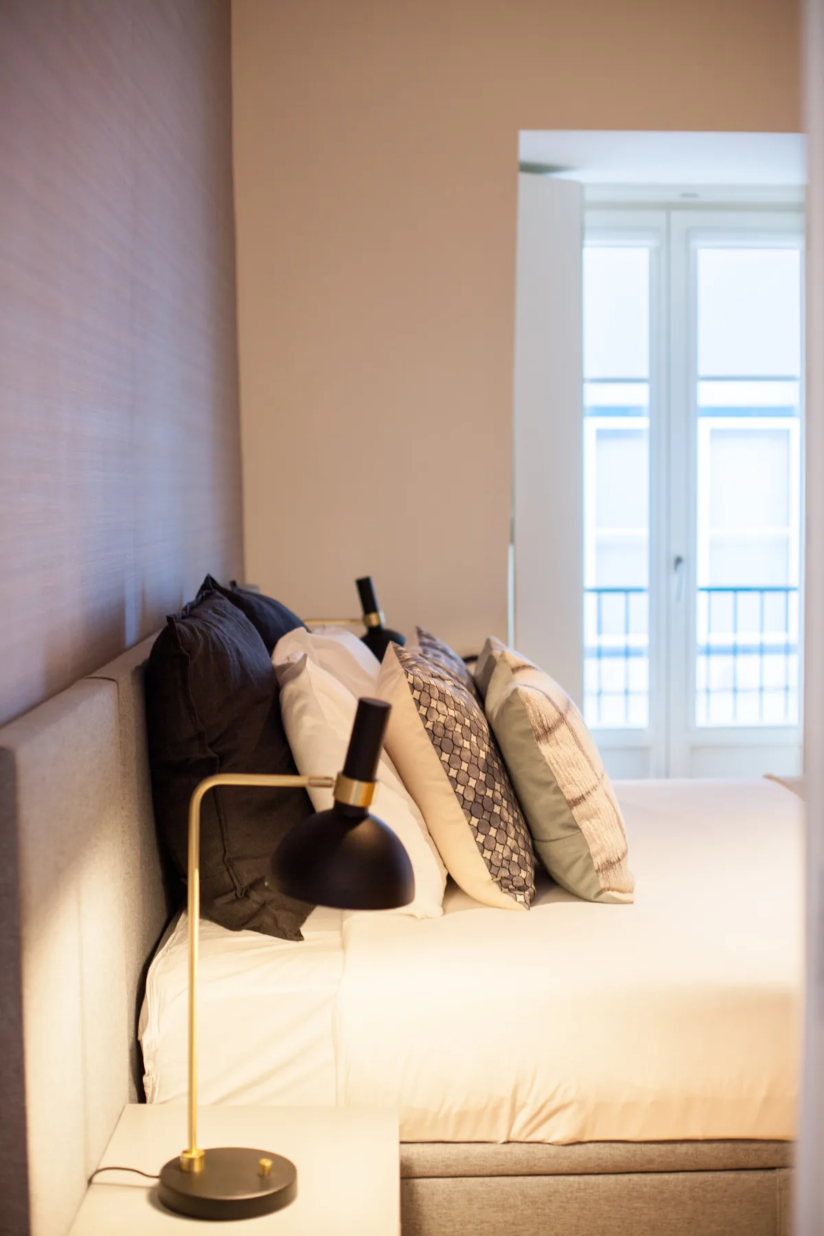 Dormitorio con una cama bien arreglada y una lámpara de mesilla.