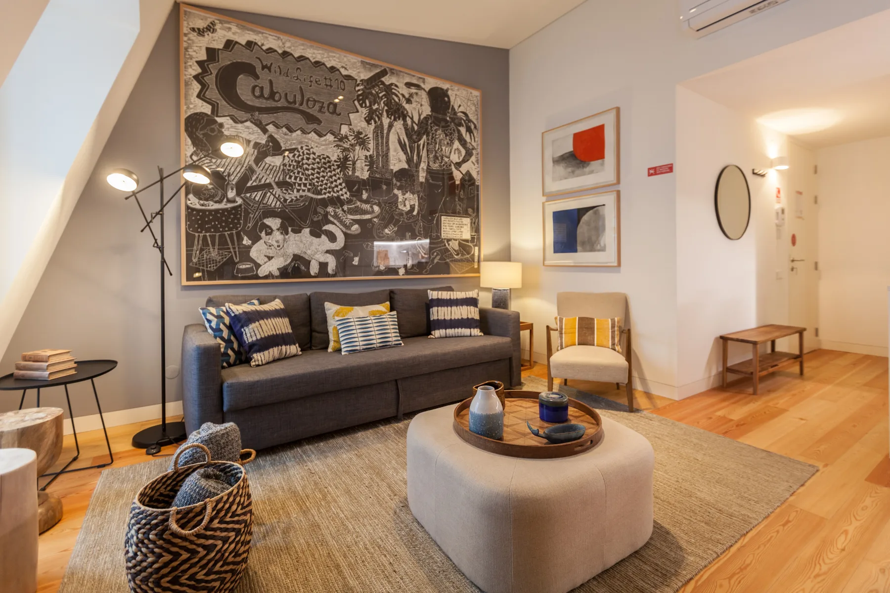 Una sala de estar con asientos, una alfombra y un gran cuadro decorativo en la pared.