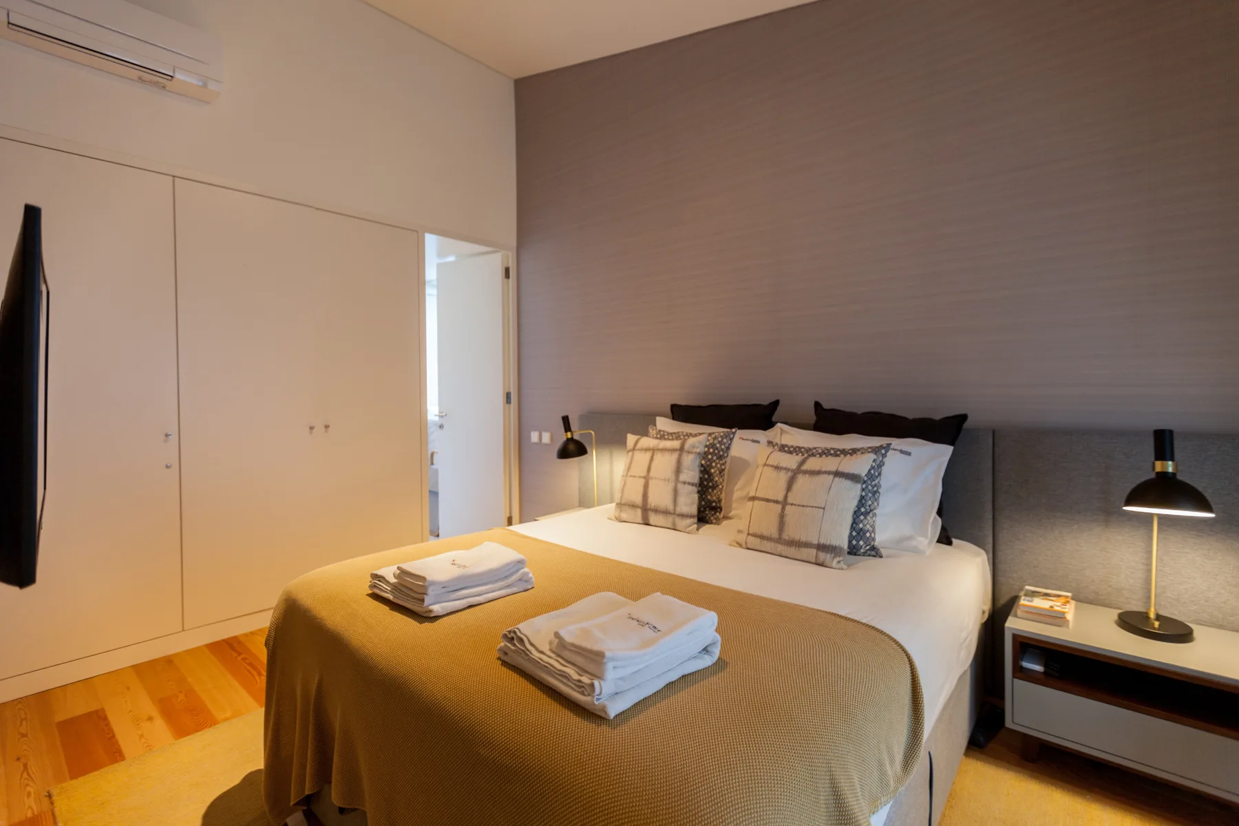 Dormitorio con una cama doble, mesillas de noche y un televisor en la pared.