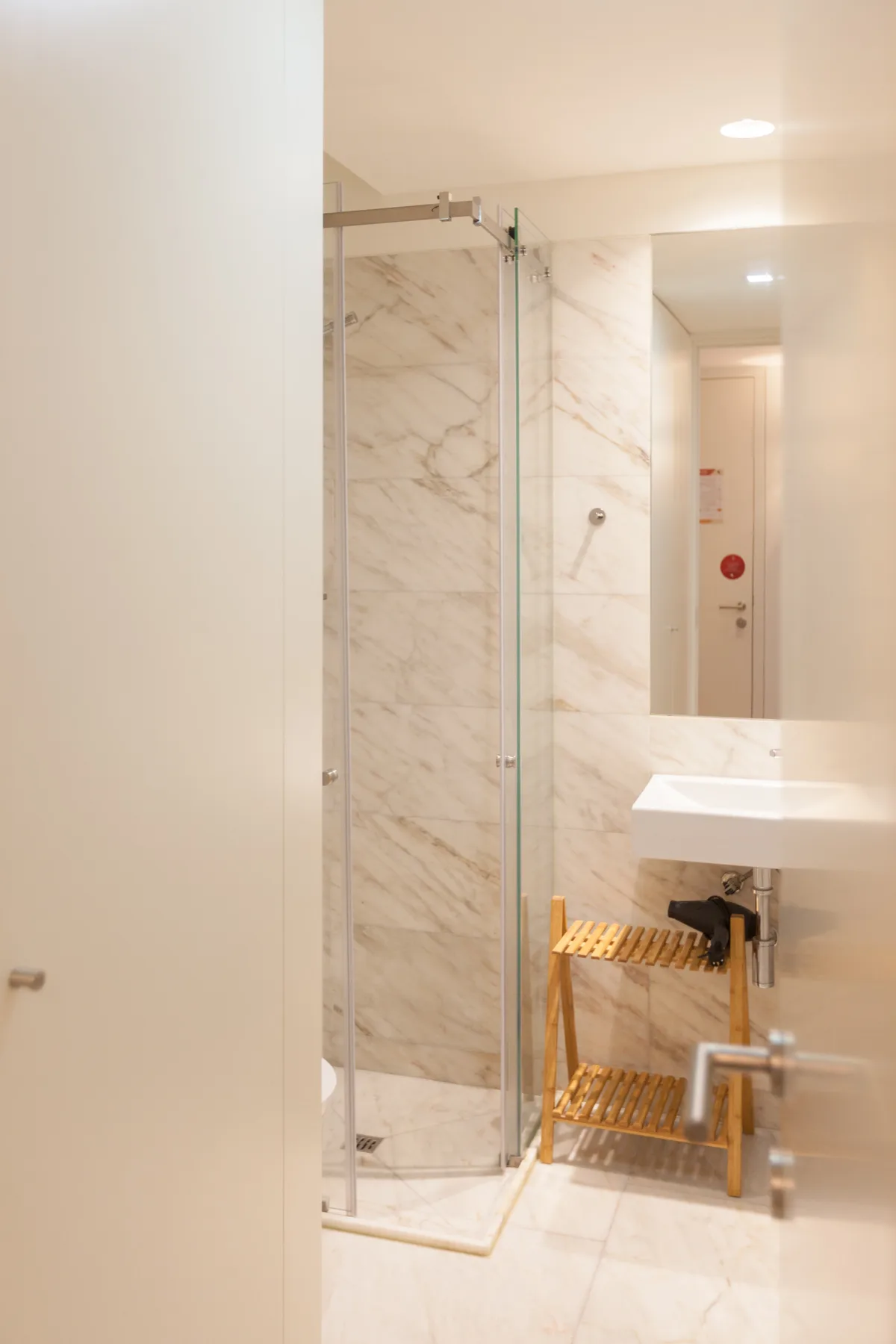 Un baño luminoso con ducha de vidrio y lavabo de pared.