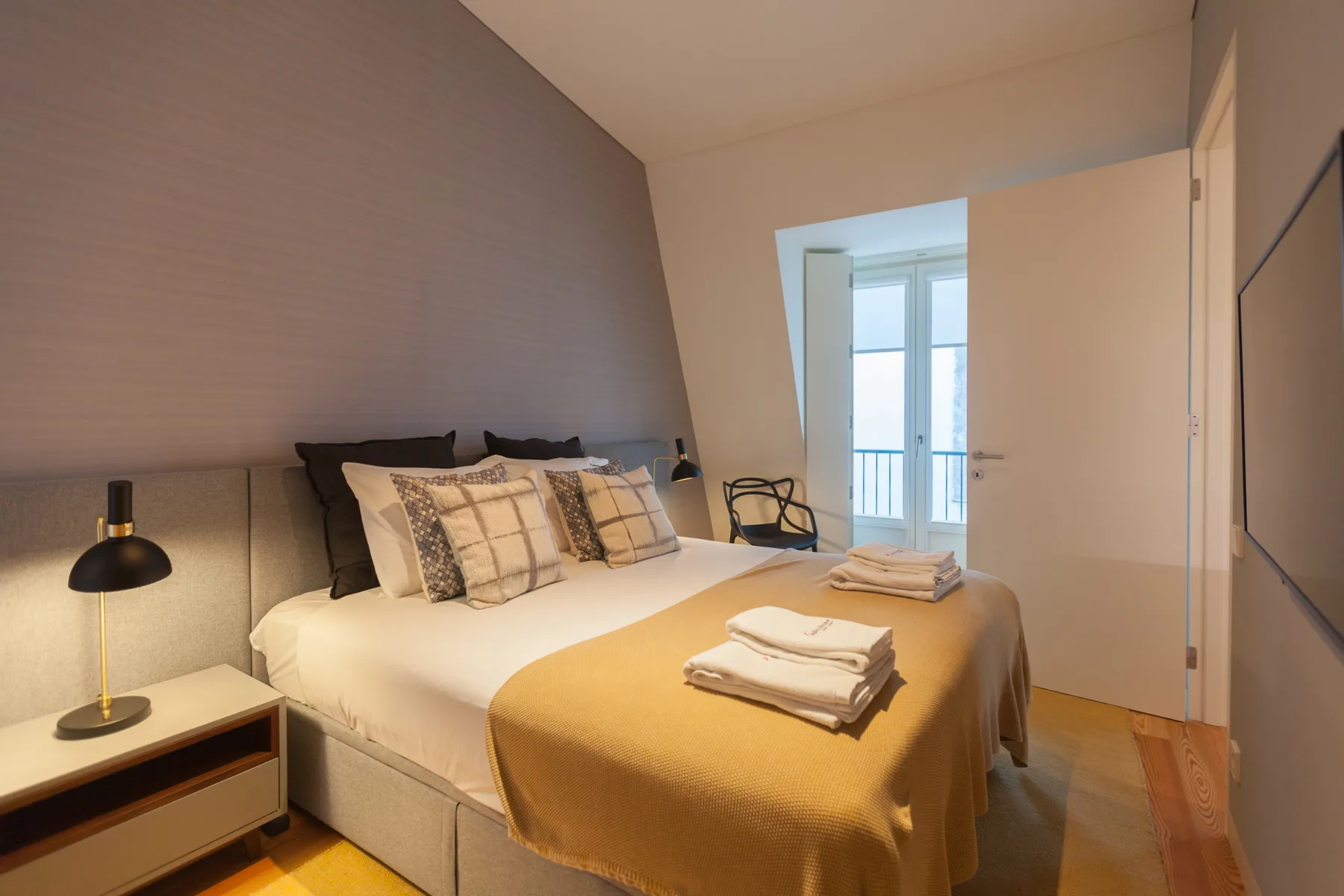 Un dormitorio con la cama bien hecha y toallas dobladas.