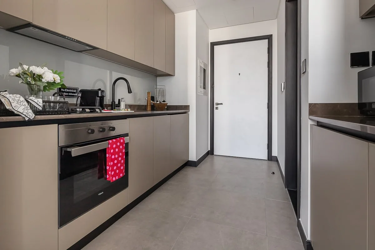Una cocina moderna con una encimera larga y una puerta blanca al fondo.