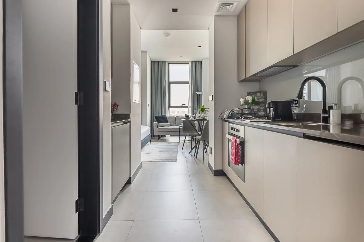 Una cocina estrecha se abre a una pequeña sala de estar con una ventana.