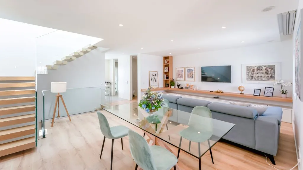 An open-plan living and dining area with a glass dining table and gray seating.