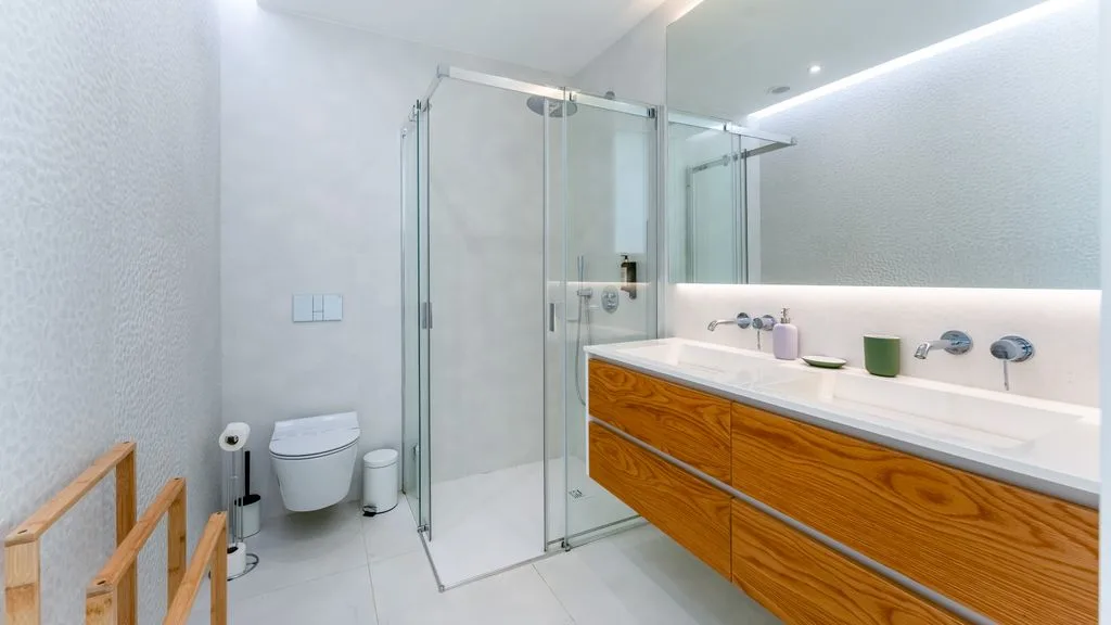 A bright bathroom with a glass shower and a long vanity.