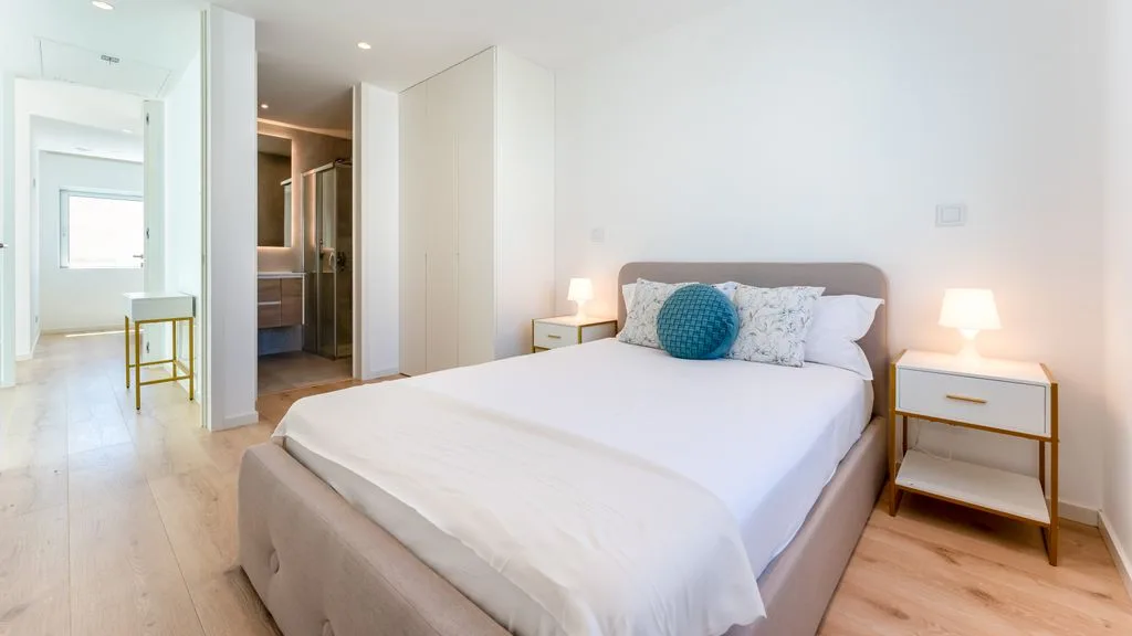 A bright bedroom with a neatly made bed and matching bedside tables.