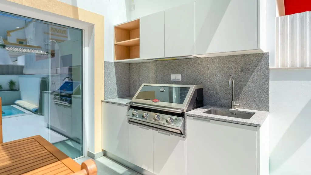 A modern kitchen with a built-in grill and gray countertop.