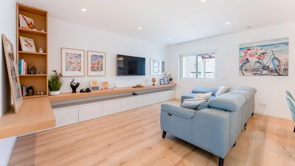 A bright living room with blue seating, wall art, and a television.