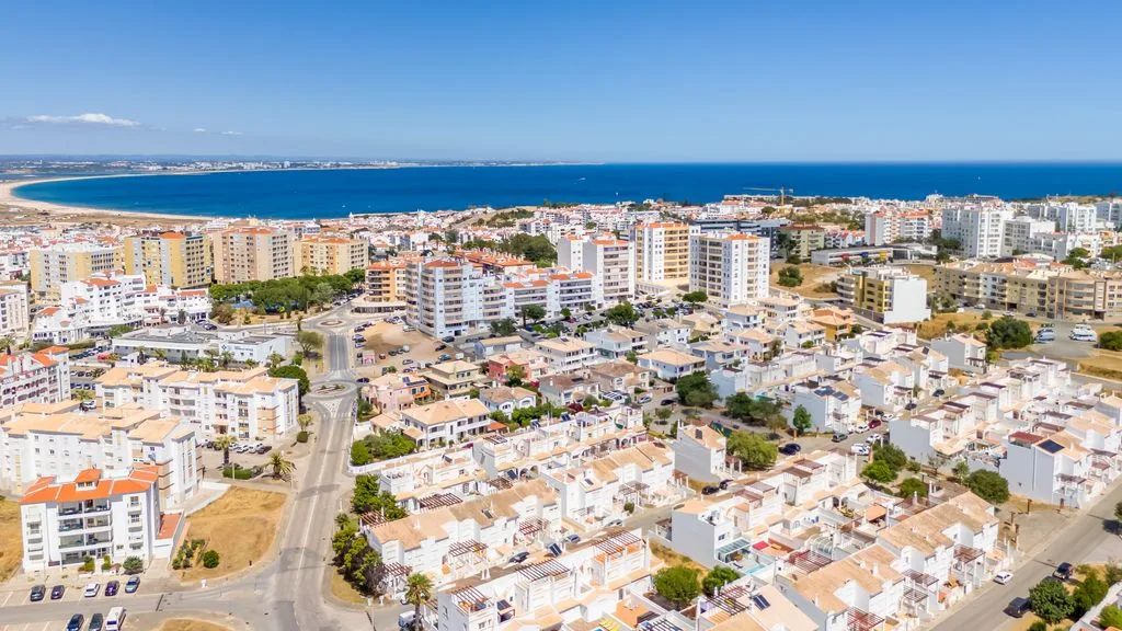 Aerial view of a coastal town with dense buildings and the sea beyond.
