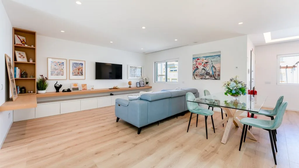 An open-plan living and dining area with a television and pale blue seating.