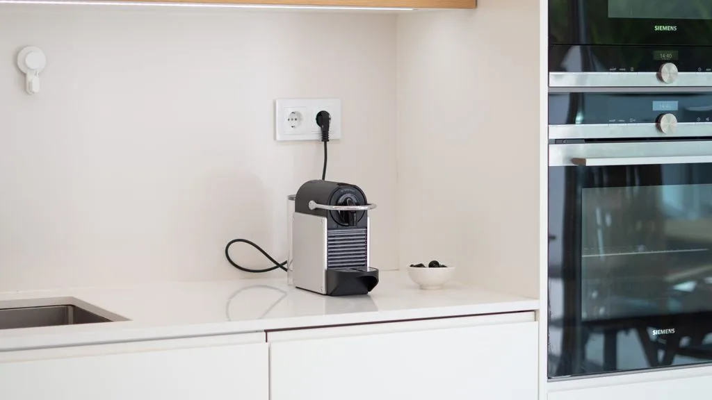 A bright kitchen counter with a coffee machine and built-in ovens.