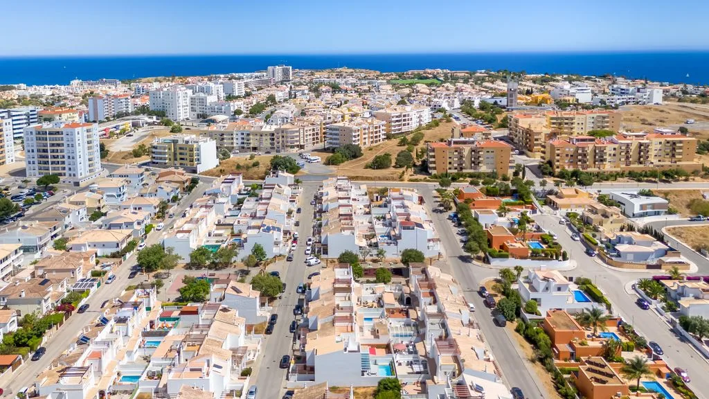 Aerial view of a coastal neighborhood with residential buildings and the sea beyond.