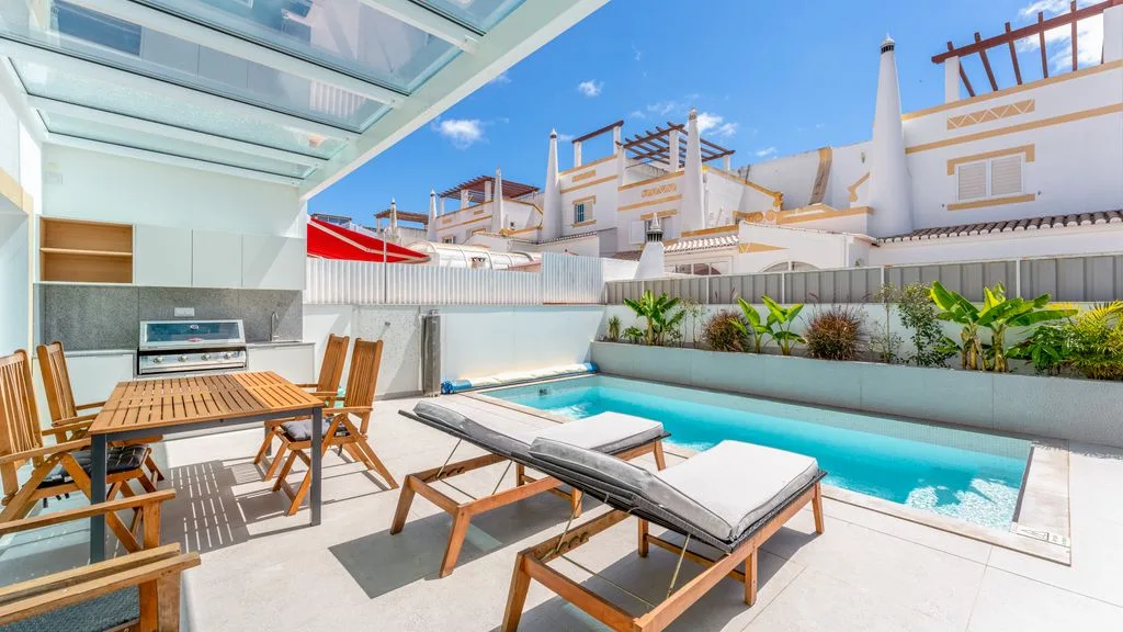 A sunny pool patio with lounge seating and an outdoor dining area.