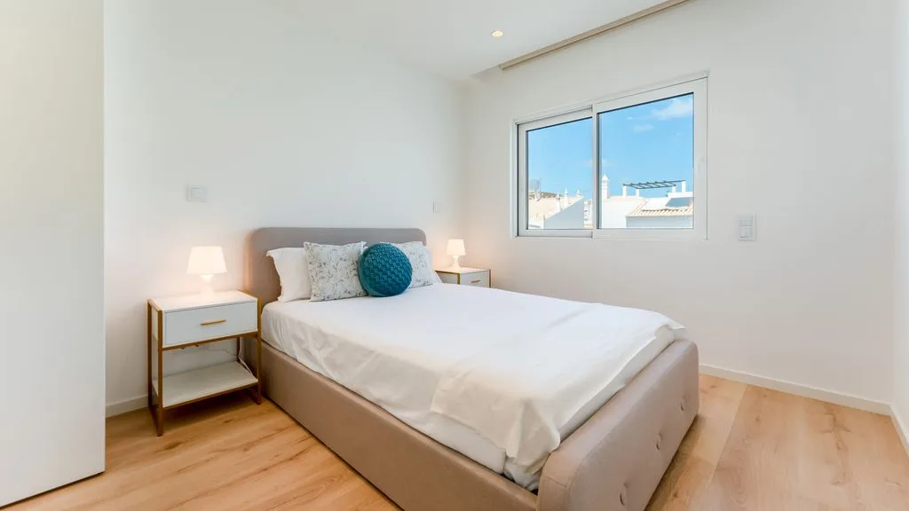 A bright bedroom with a neatly made bed and a window.