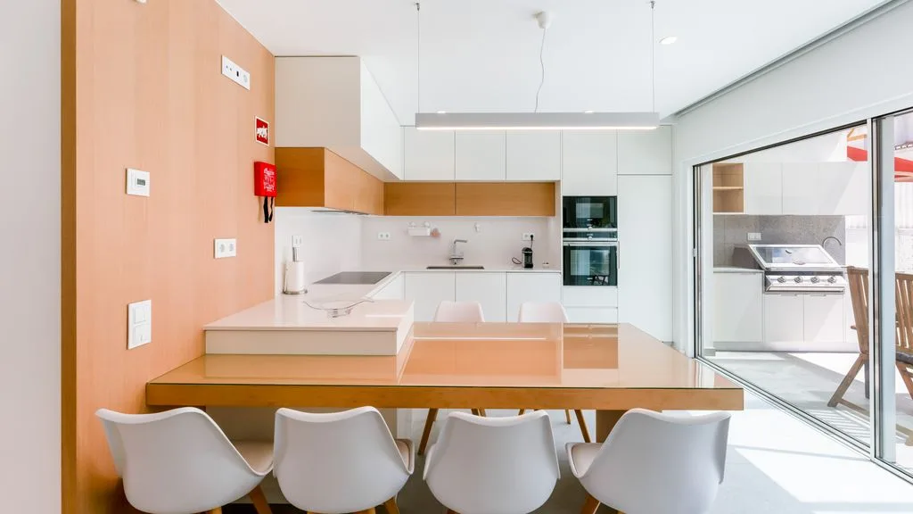 A bright modern kitchen with a dining counter and white seating.