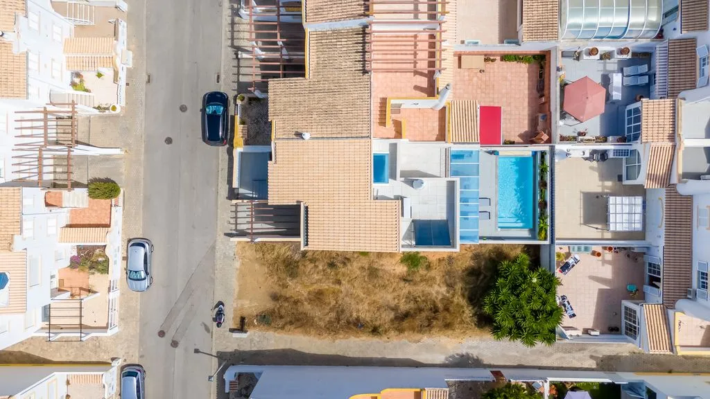 Aerial view of a residential block with a rectangular swimming pool beside a house.