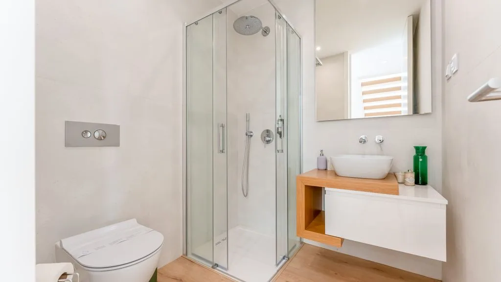 A bright bathroom with a glass shower and a wall-mounted sink.