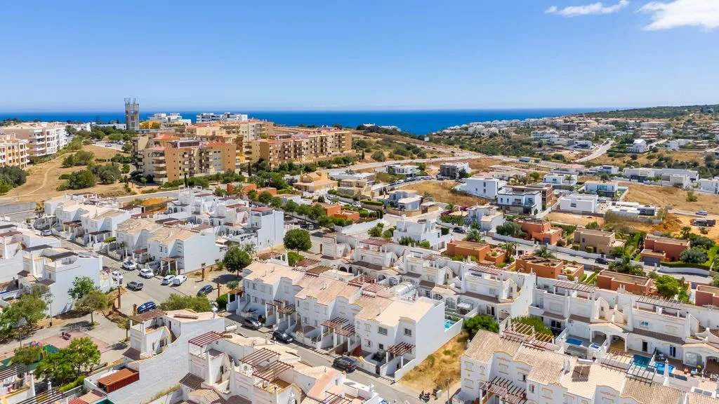 A coastal neighborhood of low-rise buildings stretches toward the blue sea.