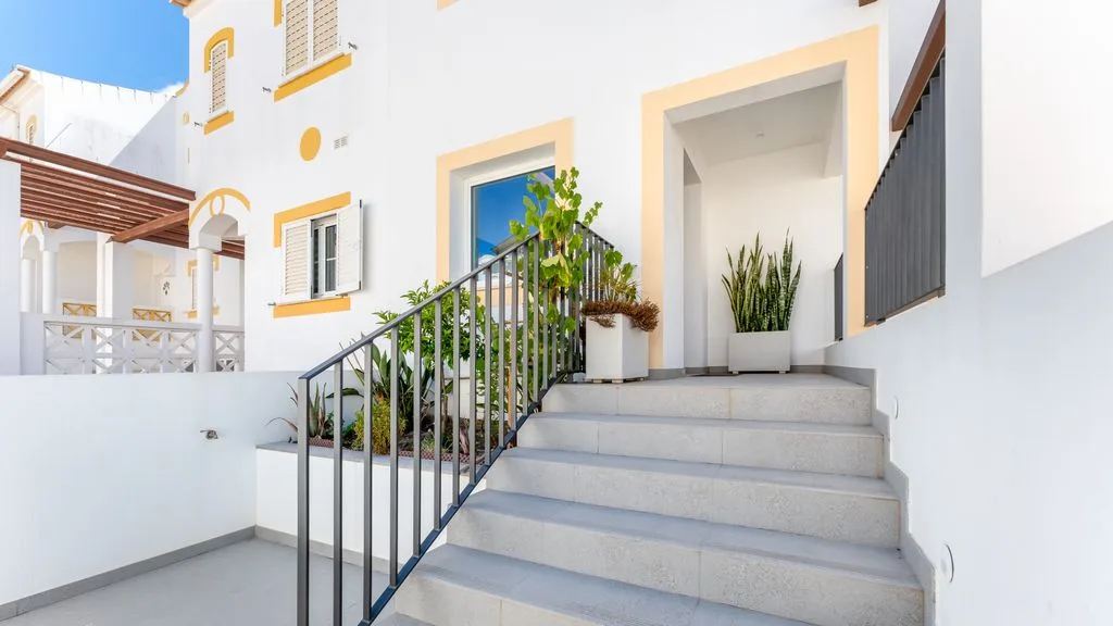 Exterior entrance steps lead to a doorway beside a potted plant.