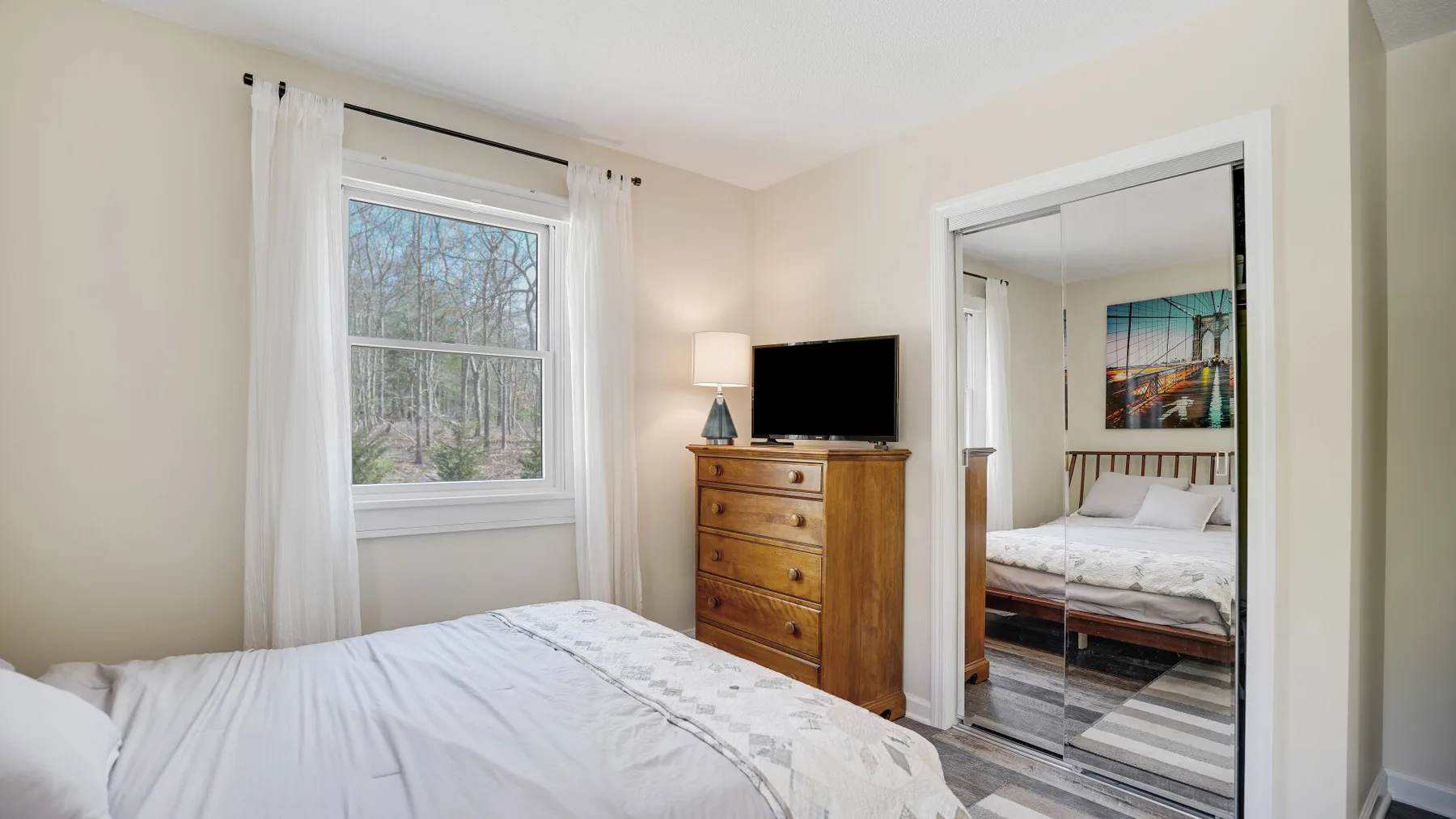 A bedroom with a bed, a wooden dresser, and a window with curtains.