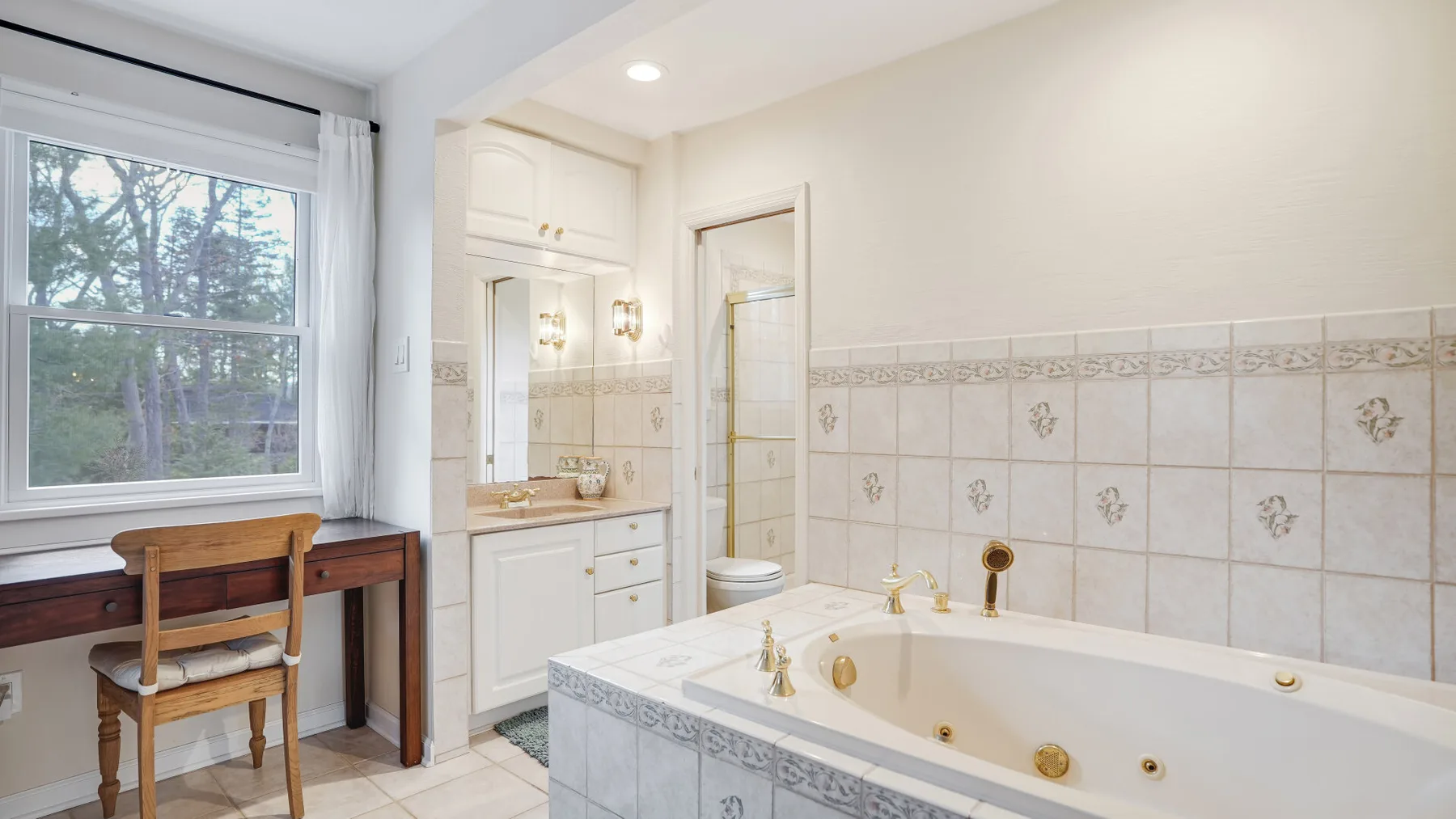 A bright bathroom with a bathtub, vanity, and window.