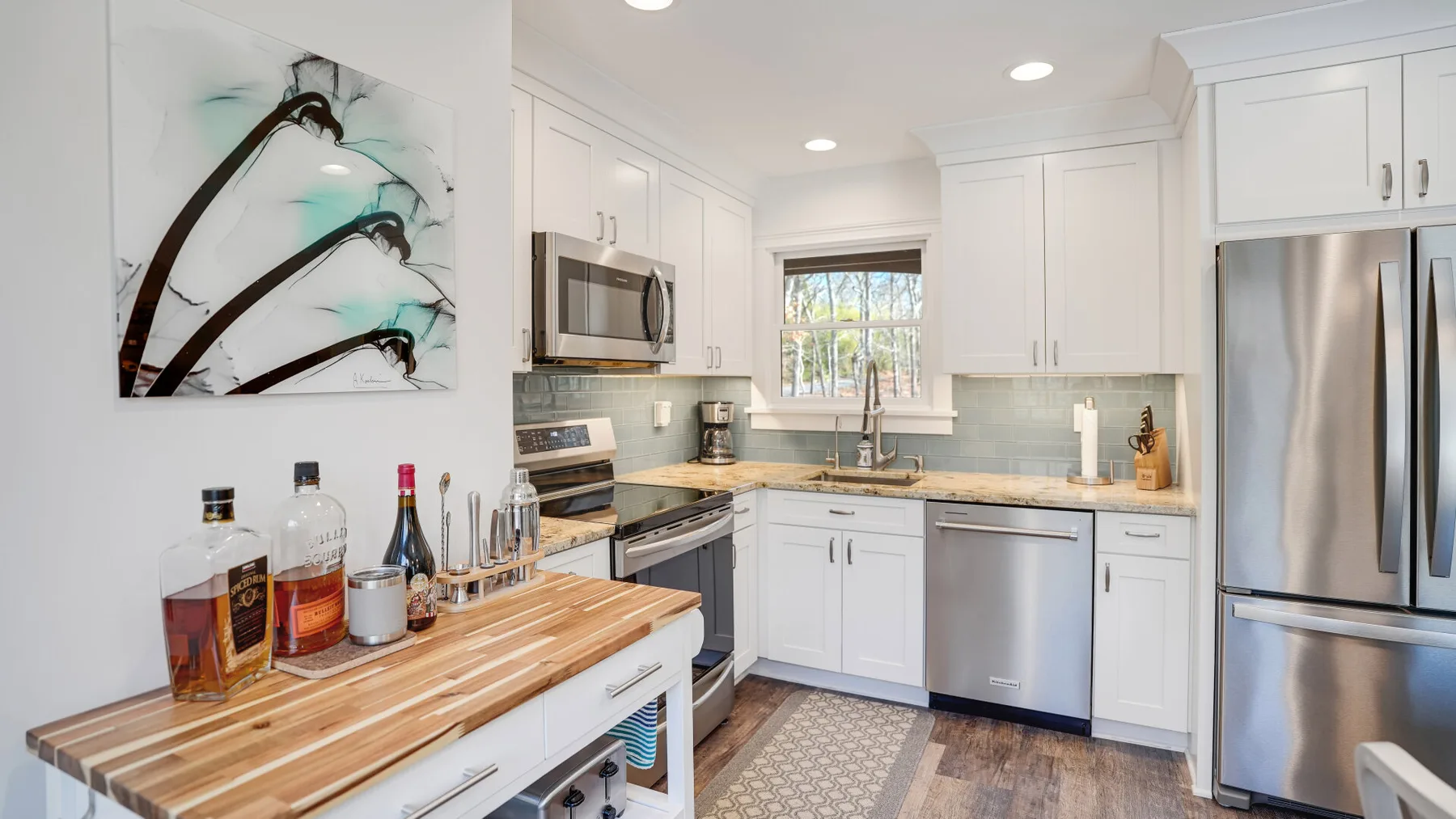A bright white kitchen with stainless steel appliances and a wood-topped island.