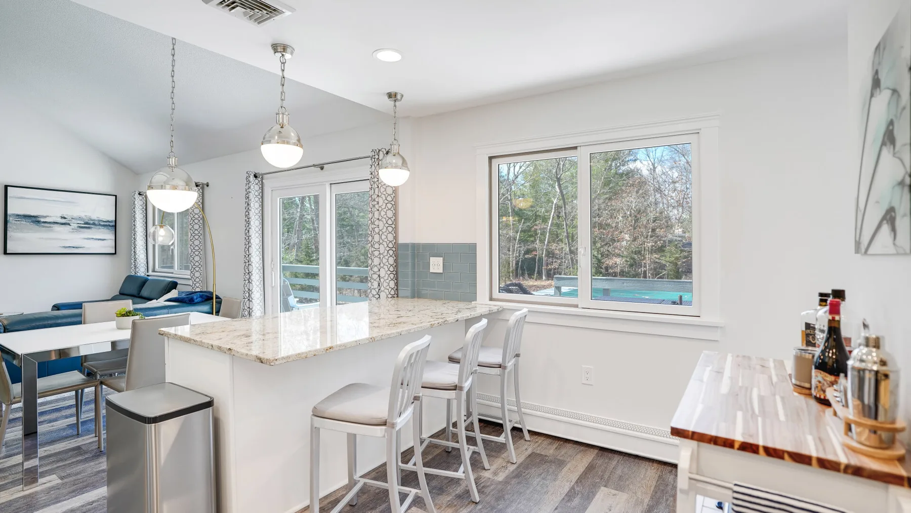 A bright kitchen with a counter and large windows overlooking trees.