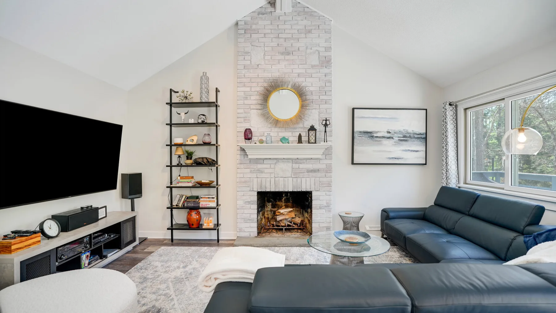 A bright living room with a fireplace, sectional seating, and a wall-mounted television.