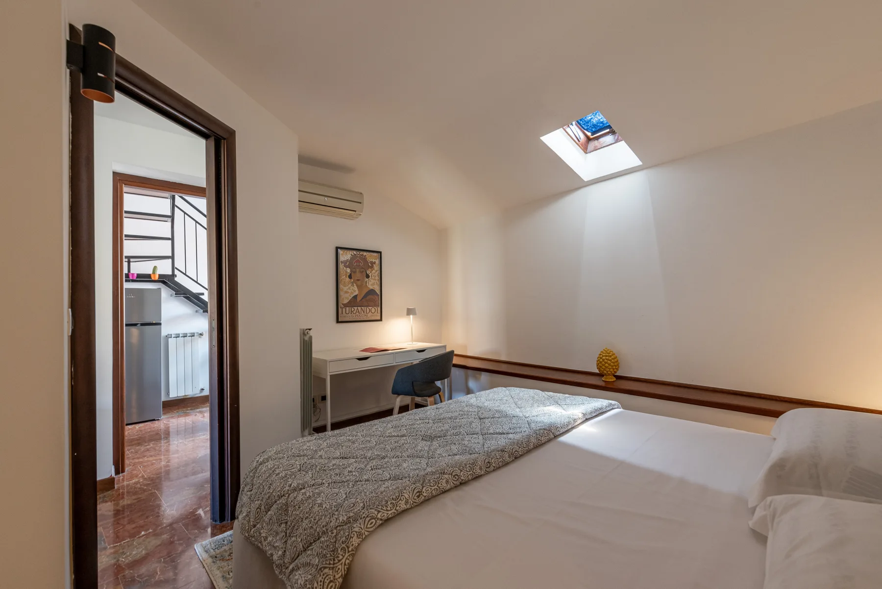 Un dormitorio con una cama, un escritorio y una claraboya.