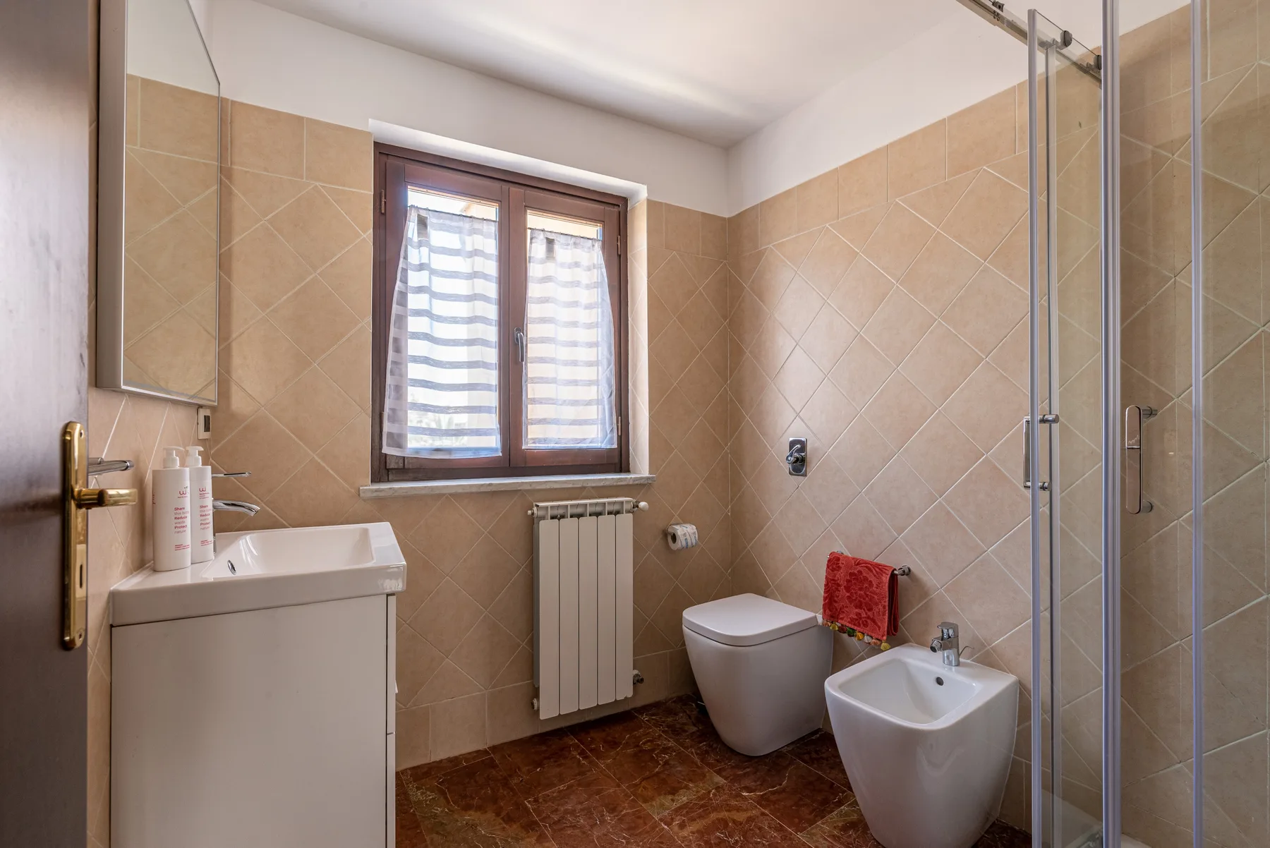 Un baño alicatado con lavabo, inodoro, bidé y ducha de vidrio.