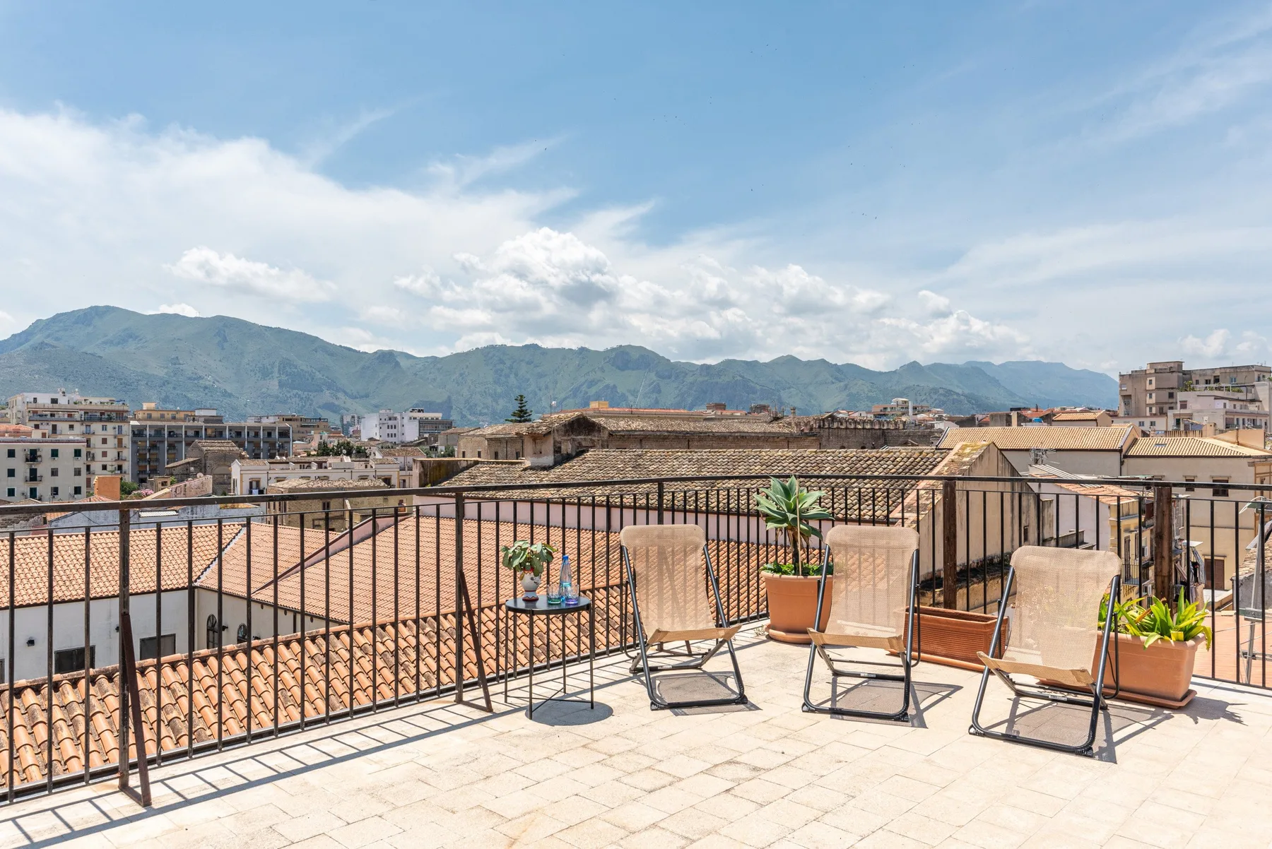 Una terraza en la azotea con asientos al aire libre ofrece vistas de la ciudad y las montañas.