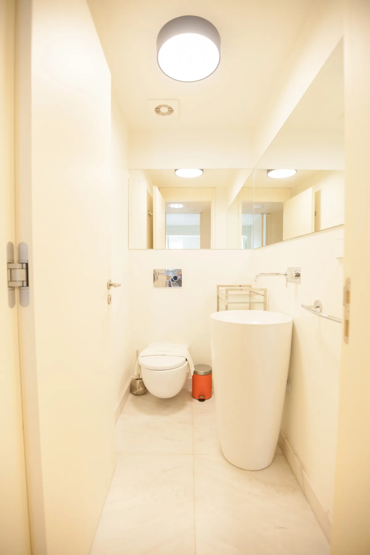 Un baño luminoso con inodoro, lavabo y un espejo grande en la pared.