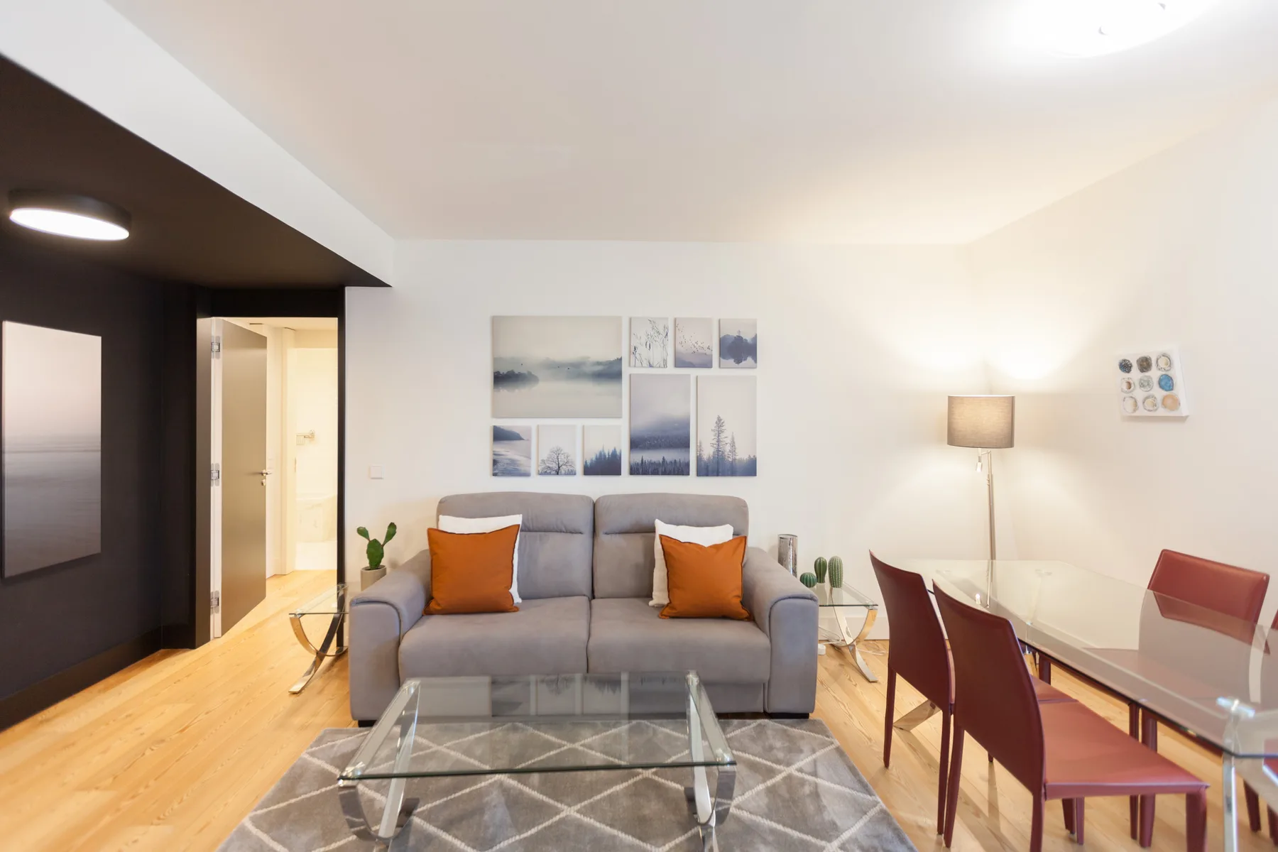 Sala de estar con asientos, una mesa de centro de vidrio y un comedor.