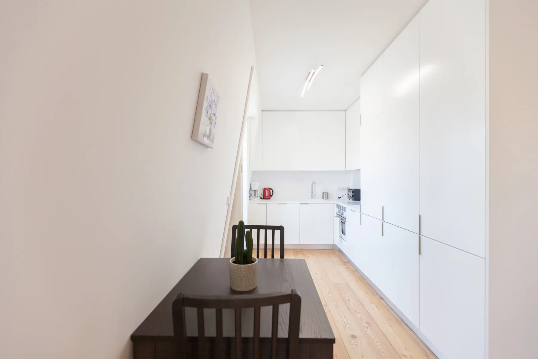 Una mesa y sillas de comedor están junto a una cocina luminosa y compacta.